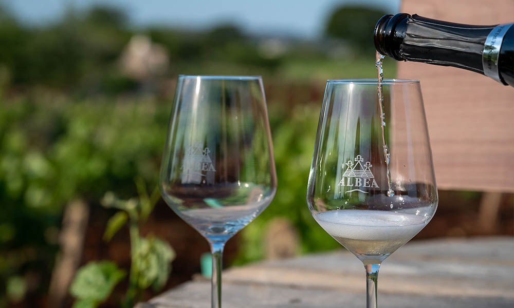 Spumante versato nei calici Albea tra i vigneti
